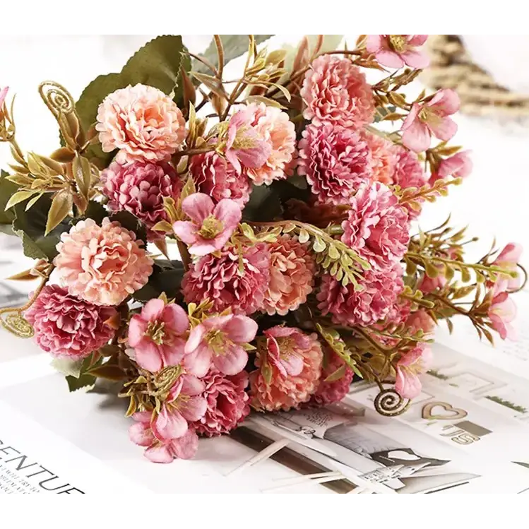A delicate bouquet of artificial pink and peach-colored flowers with green leaves, arranged in a naturalistic cluster.