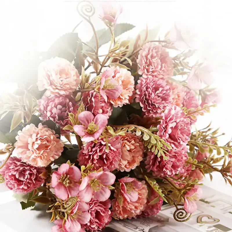 A lush bouquet of artificial pink and peach roses with green leaves and delicate spiral stems.