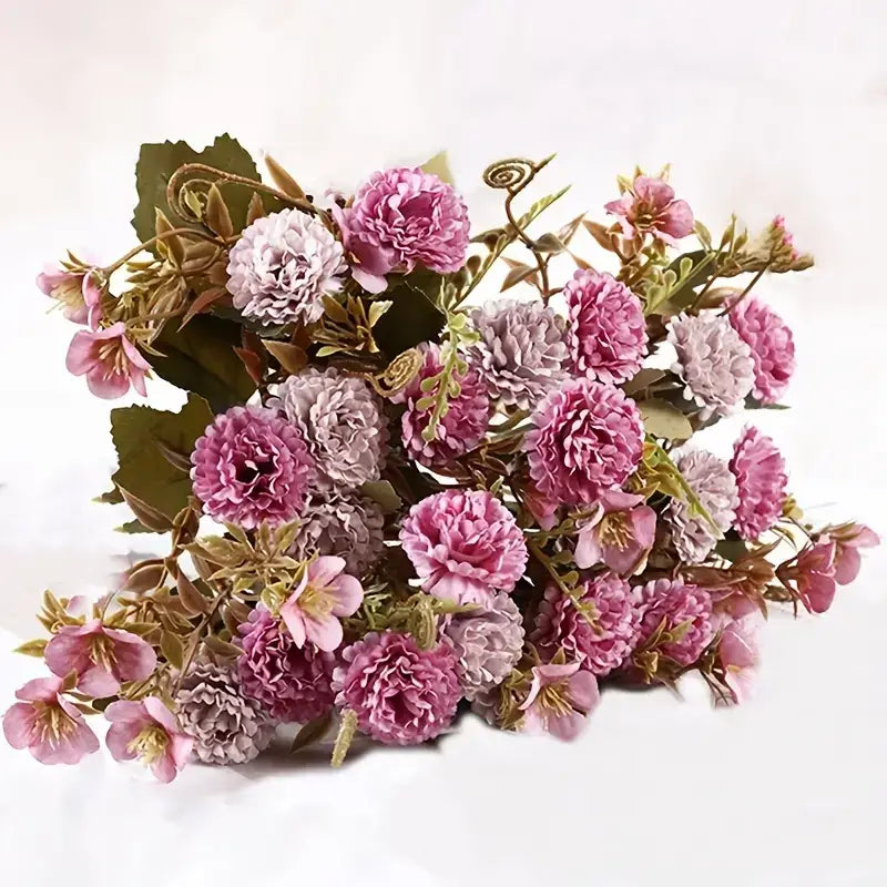 A bouquet of artificial flowers in shades of pink and lavender with green leaves and stems.