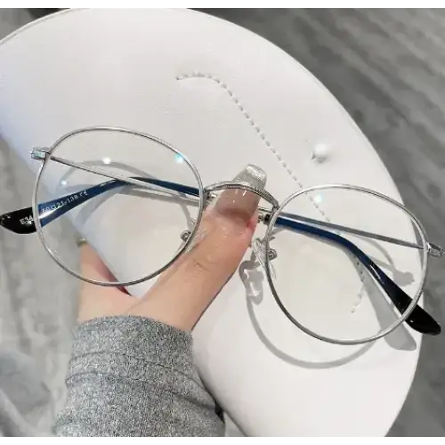 Silver-framed round glasses with black temple tips, resting on a white cap.