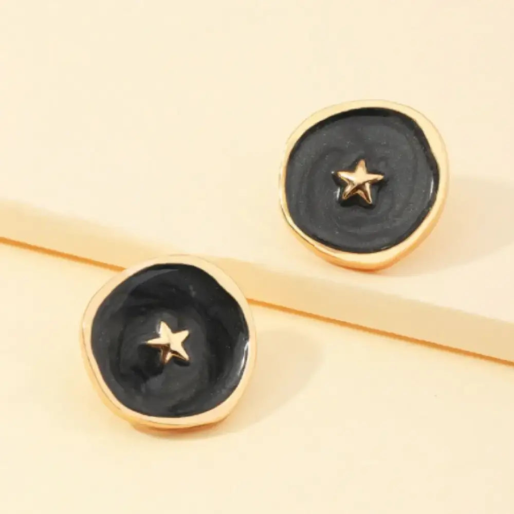 Black enamel button earrings with gold-tone star centers and rounded edges.