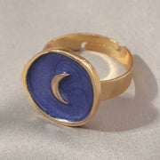 Gold-toned adjustable ring featuring a circular blue enamel face with a glittery texture and a raised crescent moon design.