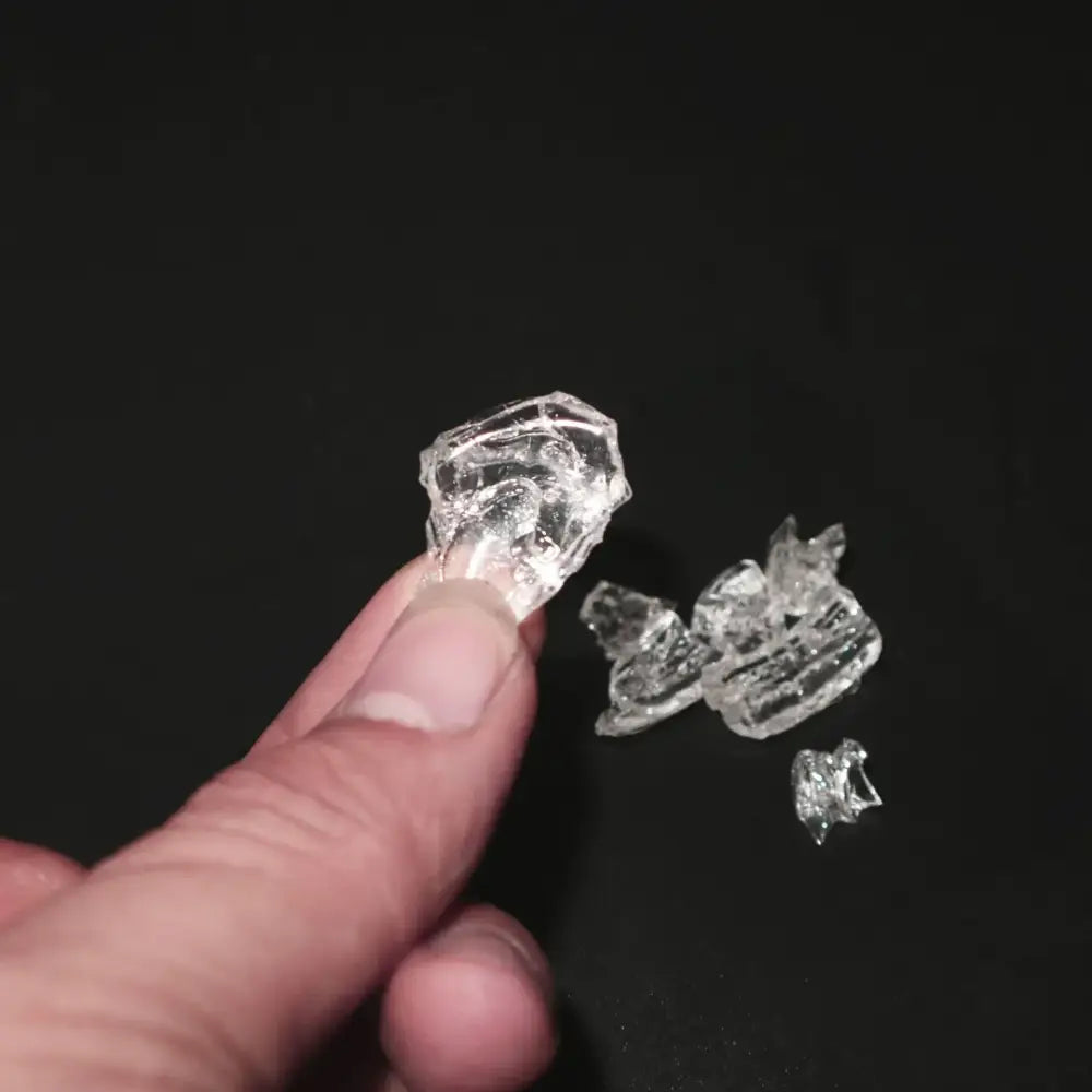 Clear, irregularly shaped glass shards held between fingers.