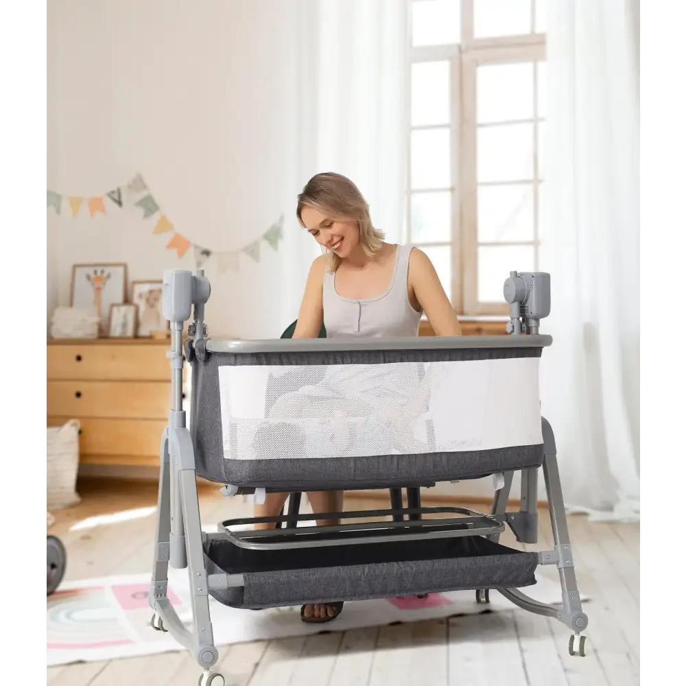 Gray and white convertible baby bassinet with mesh sides, metal frame, and storage shelf below.