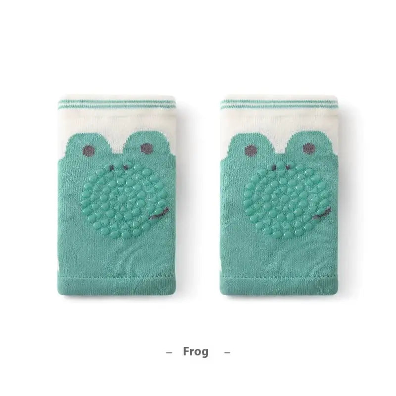 Teal frog-themed baby knee pads with textured, raised bumps on the belly and dark brown embroidered eyes.