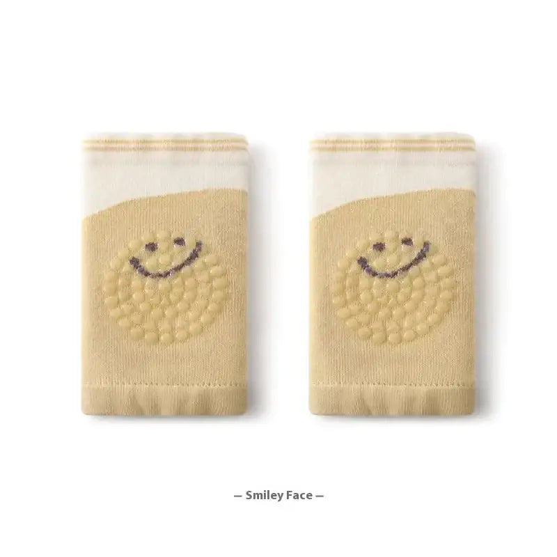 Beige knit socks with a smiling face design in dark brown, featuring textured dots and striped cuffs.