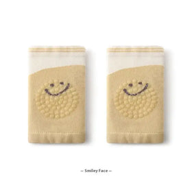 Beige knit socks with a smiling face design in dark brown, featuring textured dots and striped cuffs.