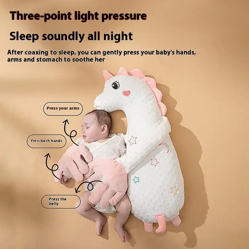 Soft white plush unicorn-shaped baby sleep aid with pink accents and star patterns.