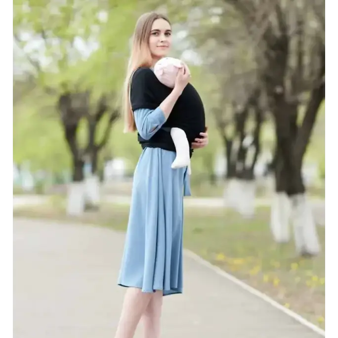 Black fabric baby carrier with light blue sleeves and matching skirt-like panel, holding a swaddled infant.