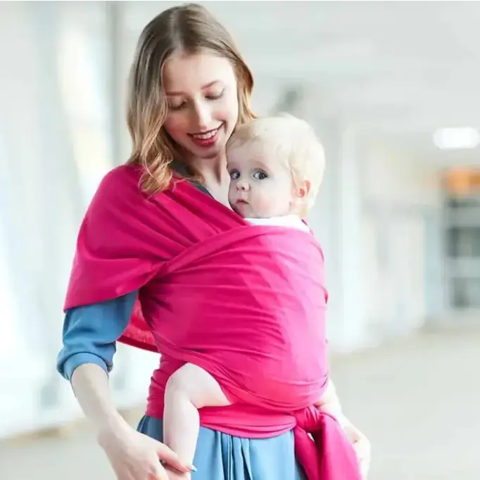 A vibrant pink woven fabric baby wrap, snugly cradling a child.