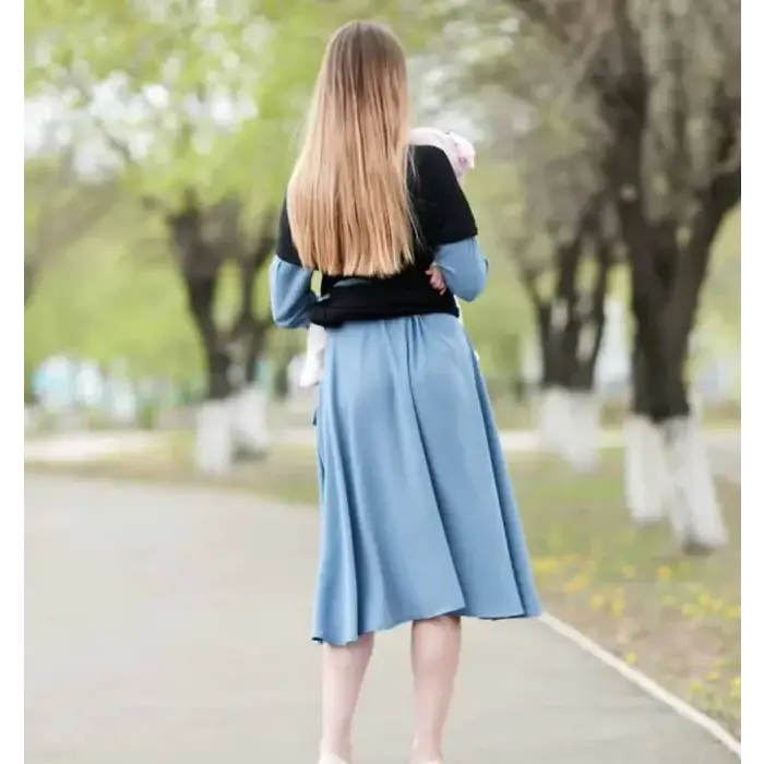A woman wearing a black and blue long-sleeved top with a flowing light-blue midi skirt.