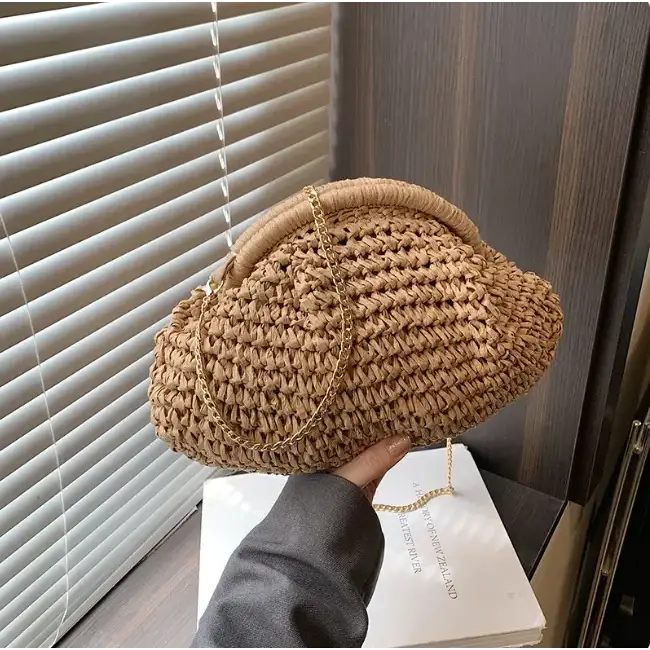 Beige woven straw clutch with a gold chain strap and a rounded, cloud-like shape.