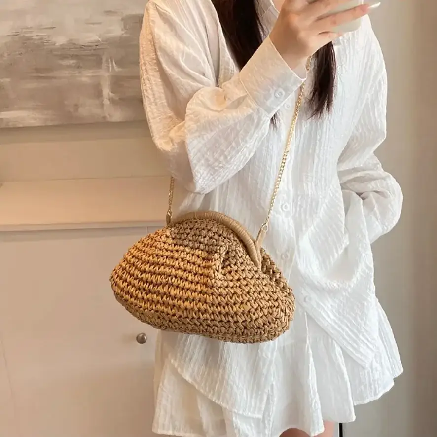 A woven straw handbag with a rounded, cloud-like shape and a gold-toned chain strap.