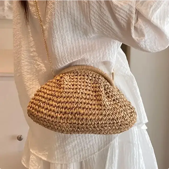 A woven straw handbag with a rounded, cloud-like shape and a gold-toned chain strap.
