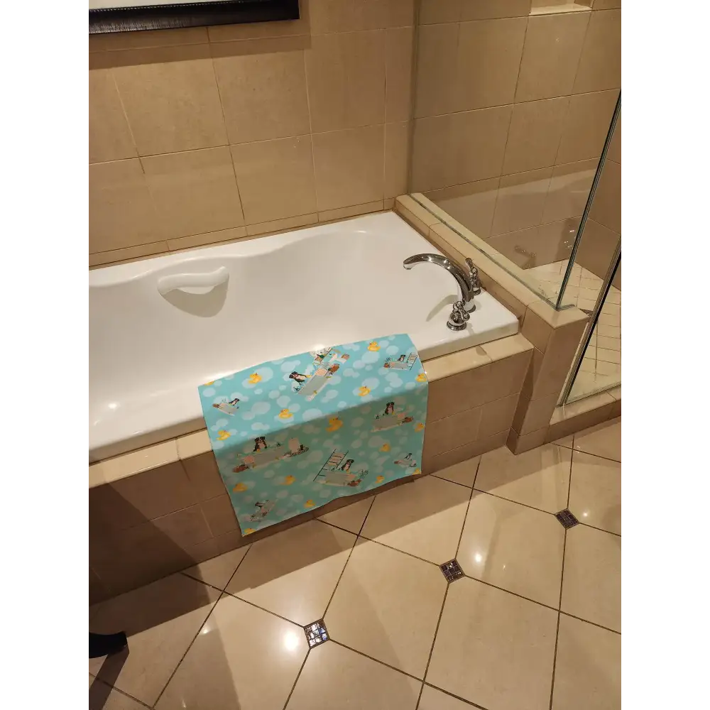 A light blue bath towel with a playful pattern of penguins, ducks, and clouds.