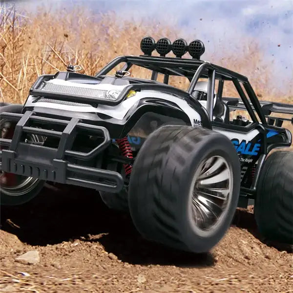 Black and silver remote-controlled off-road monster truck with large rugged tires, a reinforced front bumper, and four round lights mounted on the roof.