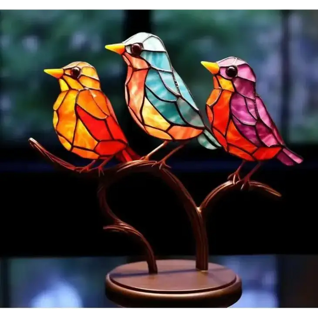 Vibrant stained glass birds in orange, teal, and pink perched on a bronze branch base.