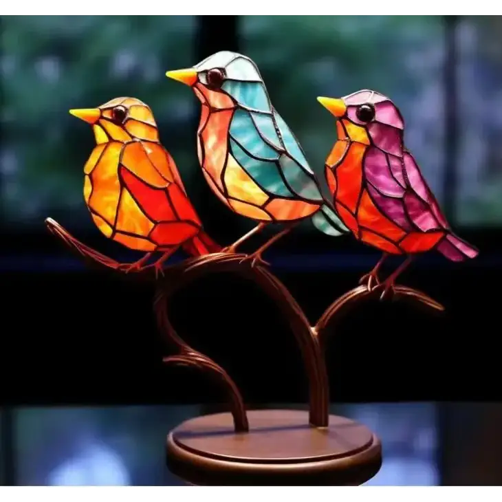 Vibrant stained glass birds in orange, teal, and pink perched on a bronze branch base.