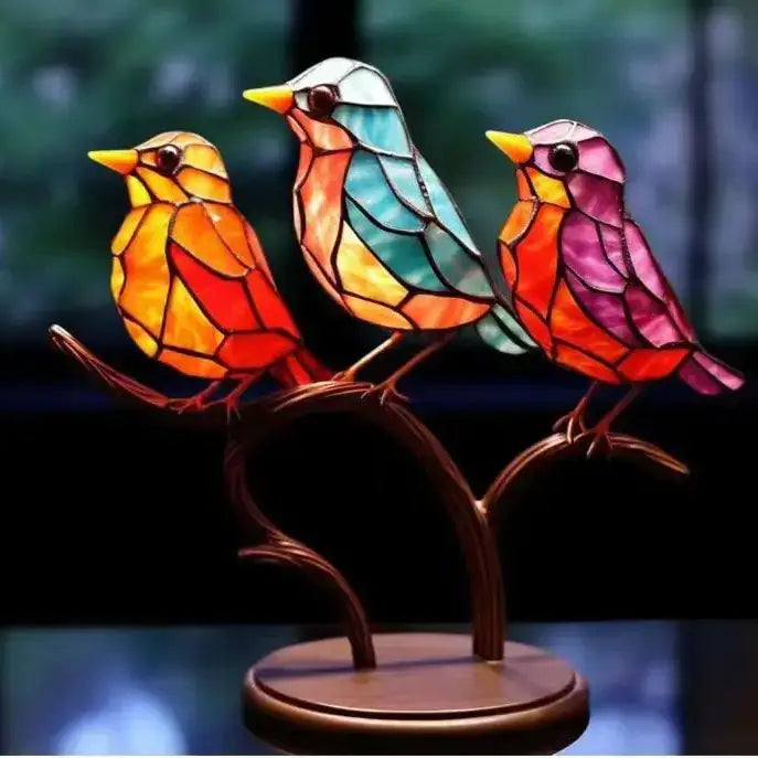 Vibrant stained glass birds perched on a bronze branch, each featuring intricate geometric patterns in warm oranges, cool teals, and rich pinks.