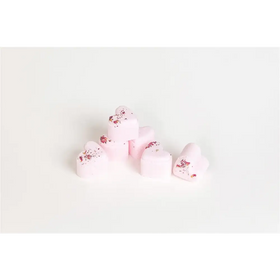 Pink heart-shaped bath bombs with dried rose petals scattered on top.