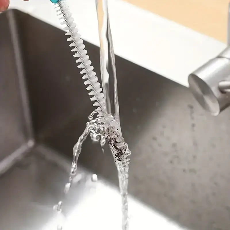 A flexible, teal-handled brush with white bristles designed for cleaning narrow spaces like faucet spouts.