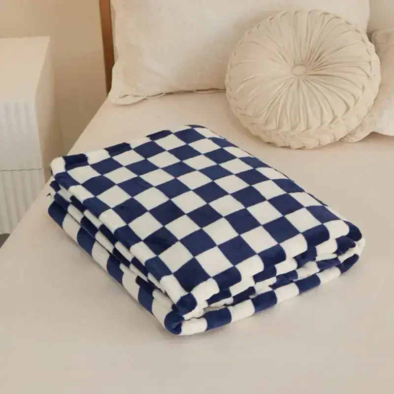 A plush navy and white checkered blanket, folded neatly on a bed.