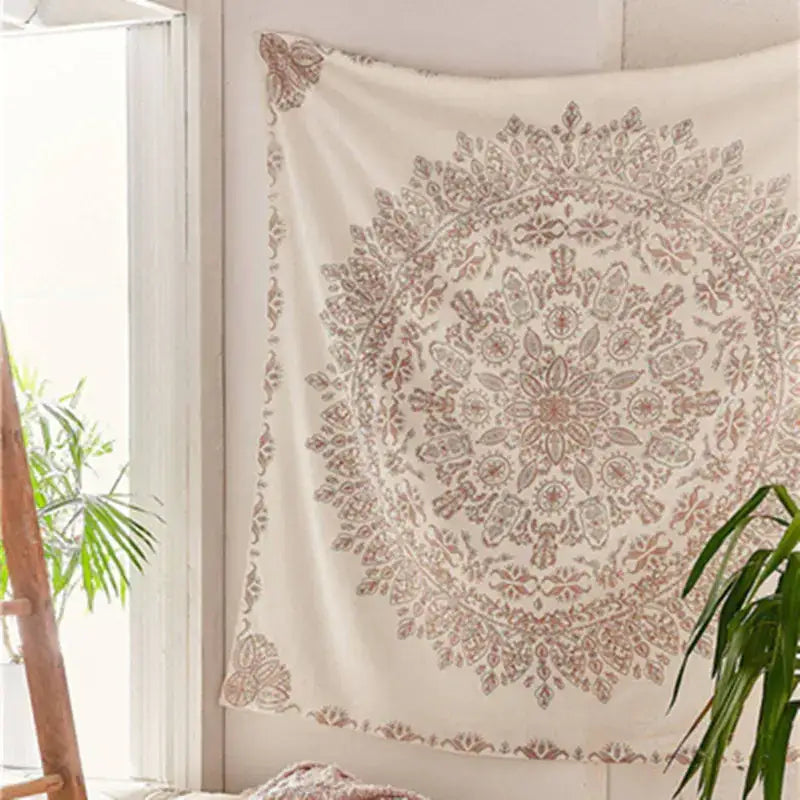 A cream-colored tapestry with an intricate, symmetrical mandala design in muted rose and beige tones.