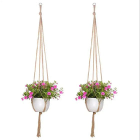 Two beige macrame hanging planters, each holding a white ceramic pot with pink flowering plants.