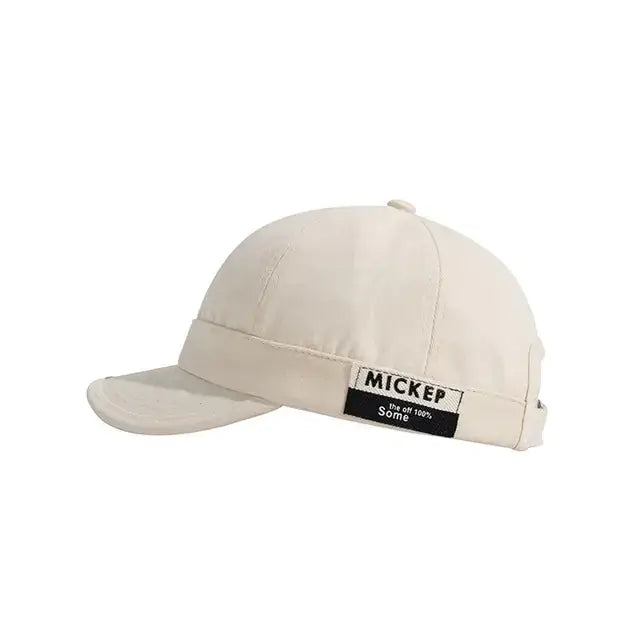 Beige baseball cap with a black label reading ’mickep’ and ’the off 100% some.’