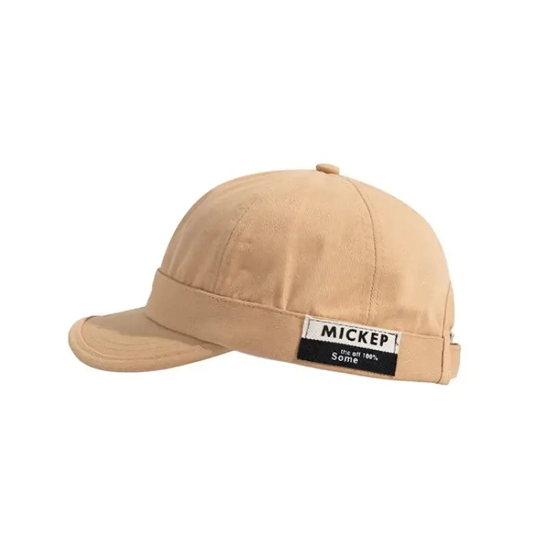Beige cotton baseball cap with a black and white label reading ’mickep’ on the brim.