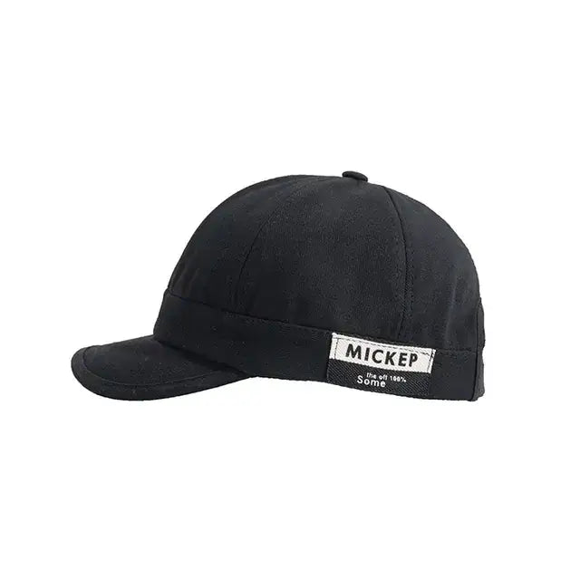 Black cotton baseball cap with a white label reading ’mickep’ and smaller text below.