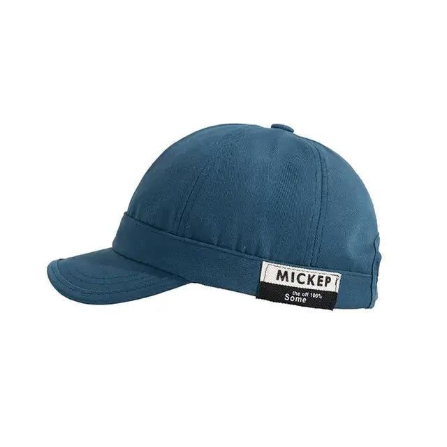 A teal-colored, six-panel baseball cap with a stitched brim and a white label on the side that reads ’mickep’ in black text.
