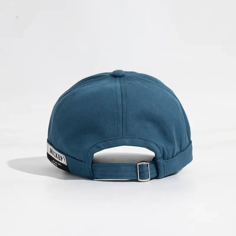 Teal-colored baseball cap with a black label reading ’micker’ and a silver buckle adjustment strap.