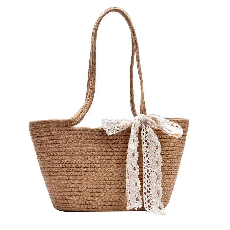 Beige woven straw tote bag with a delicate white lace bow tied at the front.