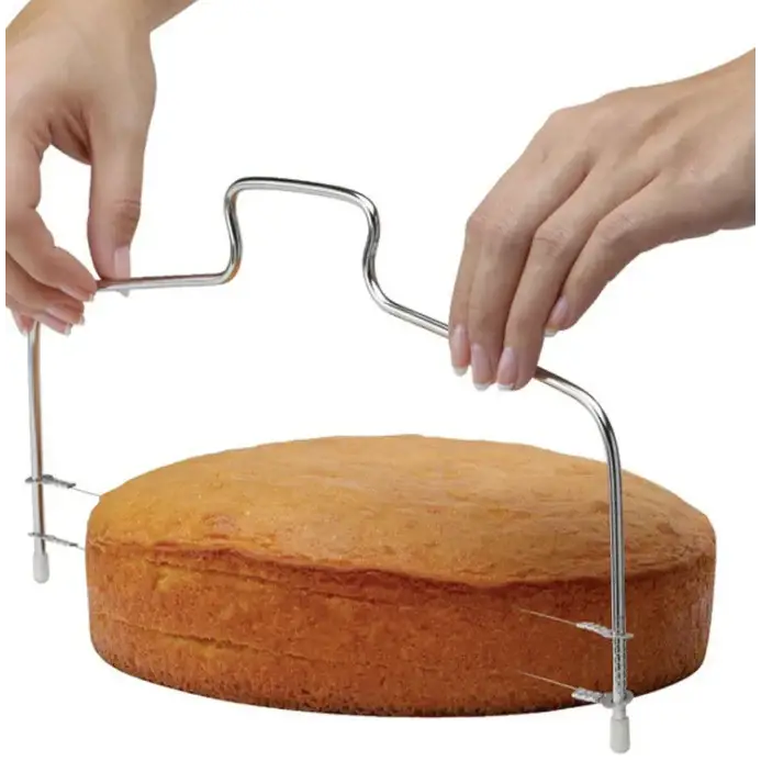 Silver metal cake slicer with a curved handle and adjustable legs for precise cutting.