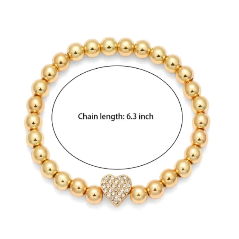 Gold-toned beaded bracelet featuring a central heart charm adorned with sparkling crystals.