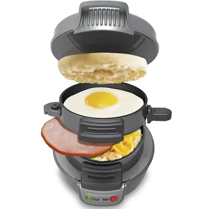 Gray electric breakfast sandwich maker with a fried egg, ham, and cheese inside