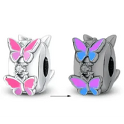 Silver butterfly charm with pink and blue enamel wings, featuring a central diamond accent.