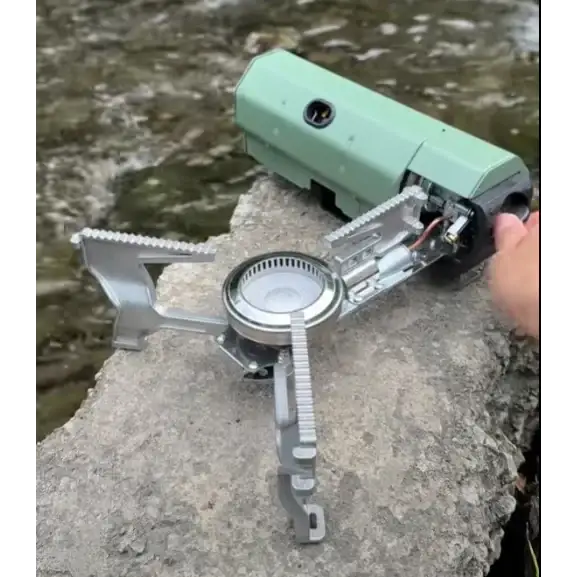 Light green and silver portable camping stove with a compact, foldable design.