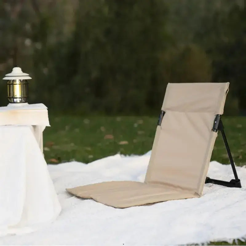 Beige fabric folding chair with black metal frame and adjustable back support.