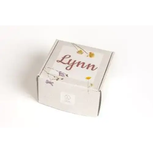A white cardboard box with a delicate floral design and the name ’lynn’ printed in elegant cursive script.