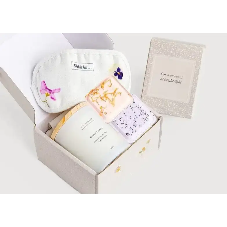 White eye mask with embroidered purple and pink flowers and a ’shhh...’ label.