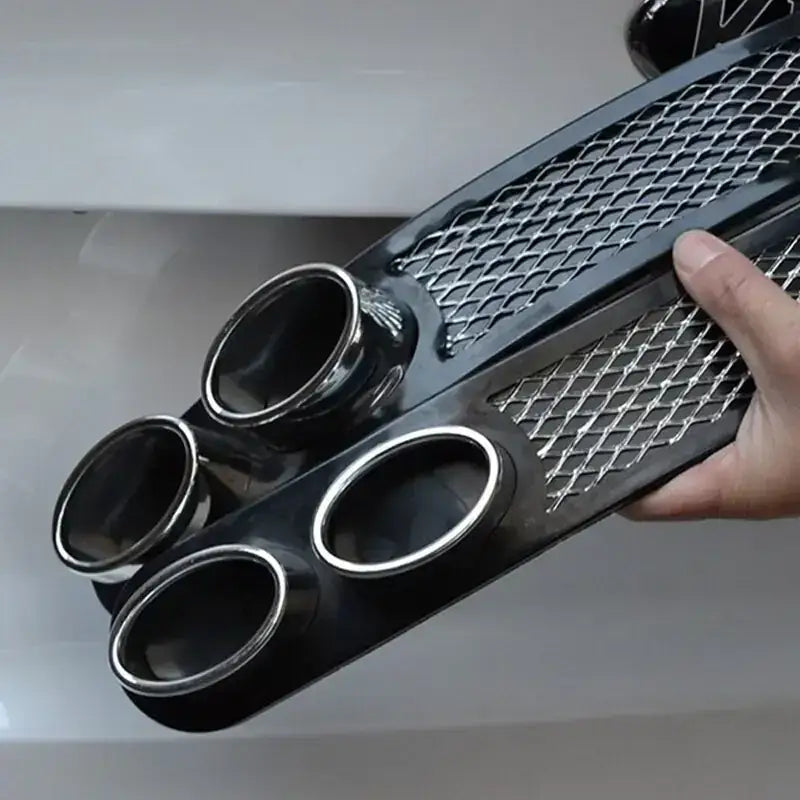 Black aftermarket exhaust tip cover with a diamond mesh grille and four polished chrome circular openings.