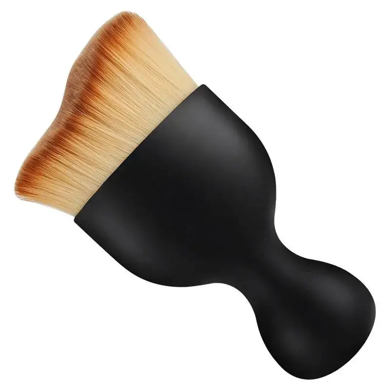 Black-handled makeup brush with soft, tapered bristles that blend from light beige to warm tan at the tips.