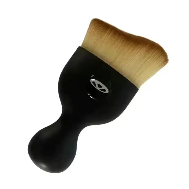 Black-handled makeup brush with dense, light brown bristles and a sleek ergonomic design.