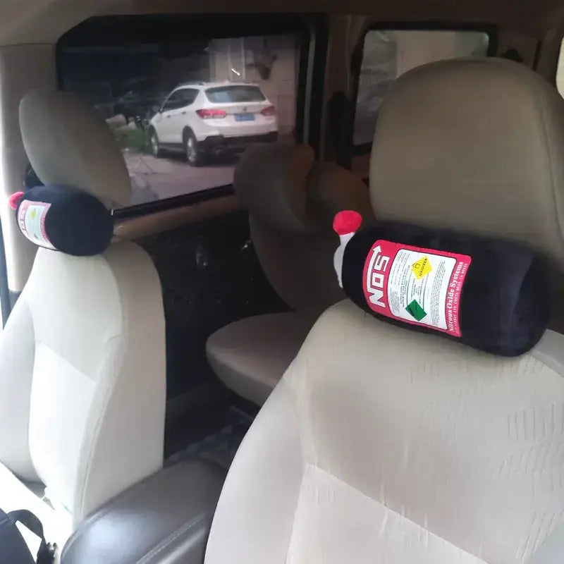 Black plush bottle-shaped headrest pillow with a red label and cap.