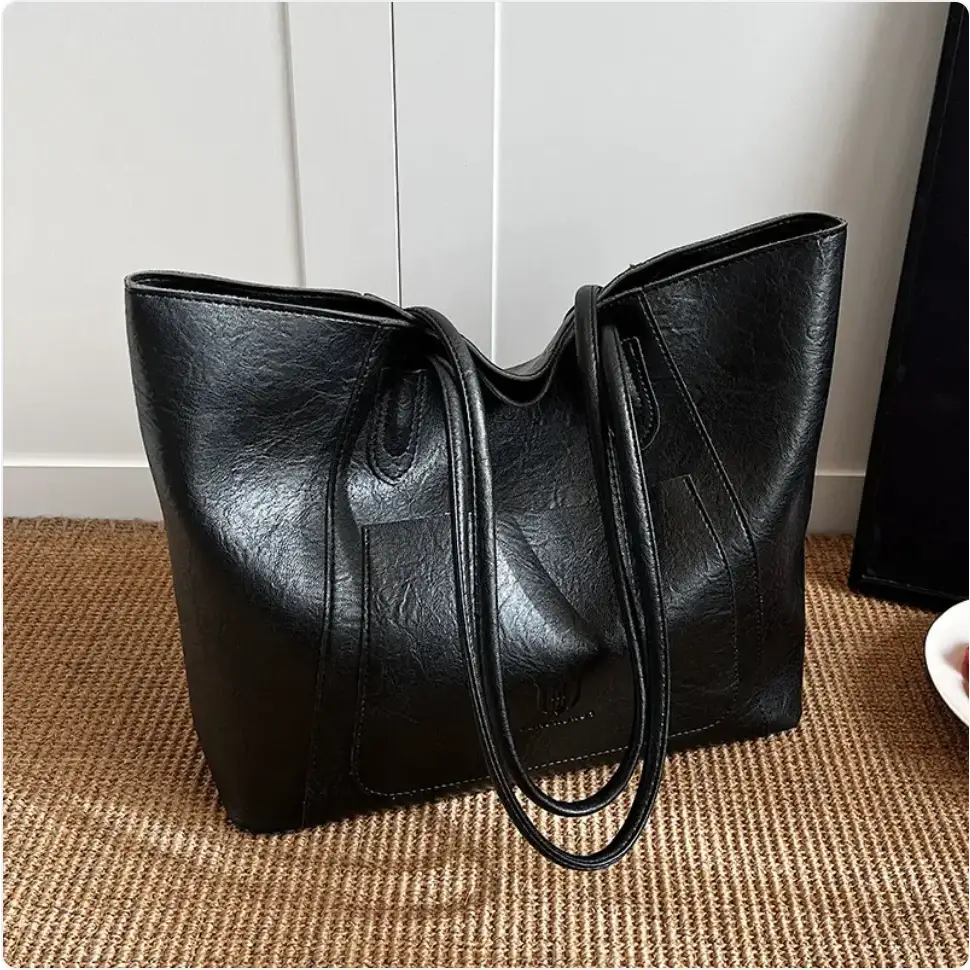 Black faux leather tote bag with a soft, slightly textured surface and sturdy handles.
