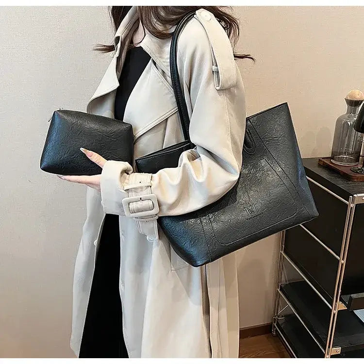 Black textured leather tote bag with a white buckle strap