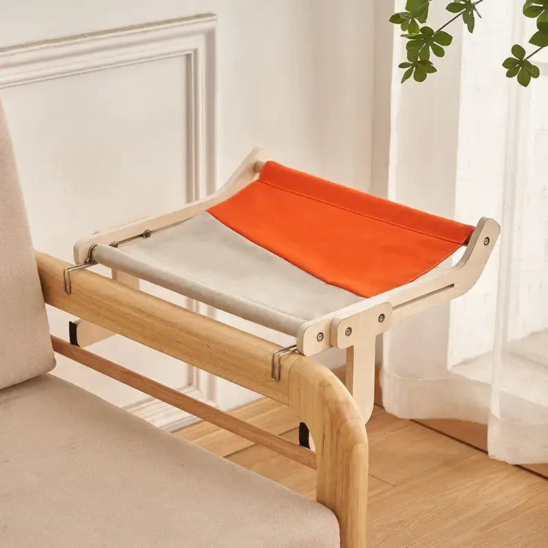 A modern wooden cat bed with a two-tone fabric top in orange and gray.