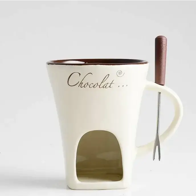 Cream-colored ceramic chocolate fondue mug with a brown rim and the word ’chocolat...’ written in elegant cursive, featuring an arched opening for dipping food.